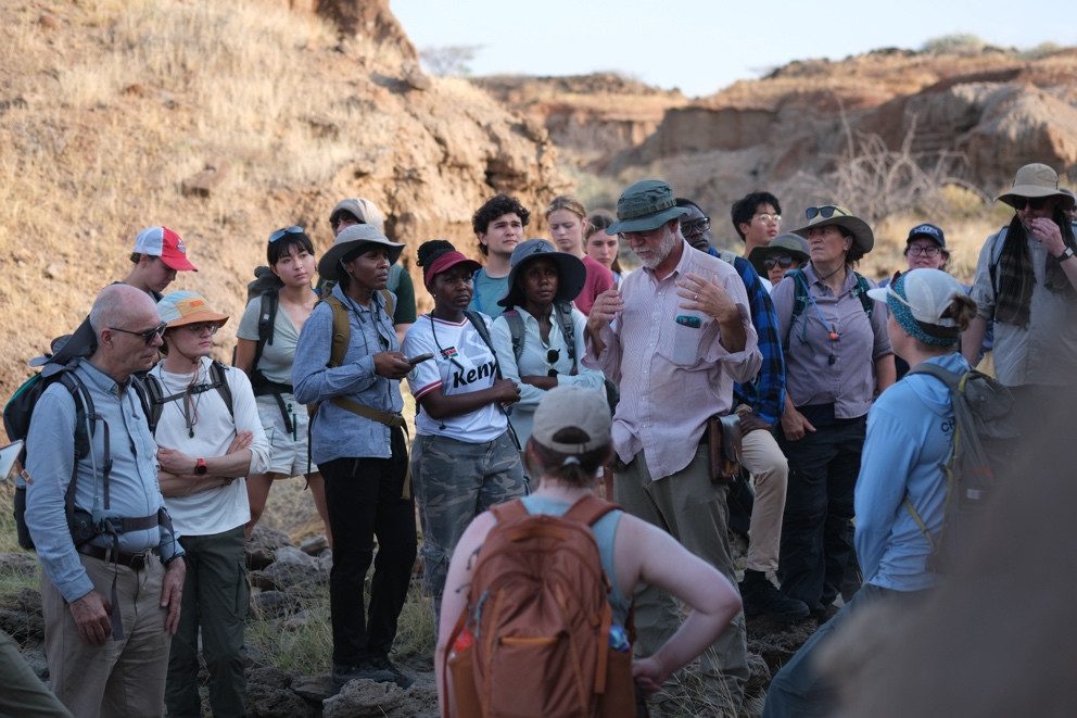 Geologist Craig Feibel explaining rock strata to a group of students and scientists